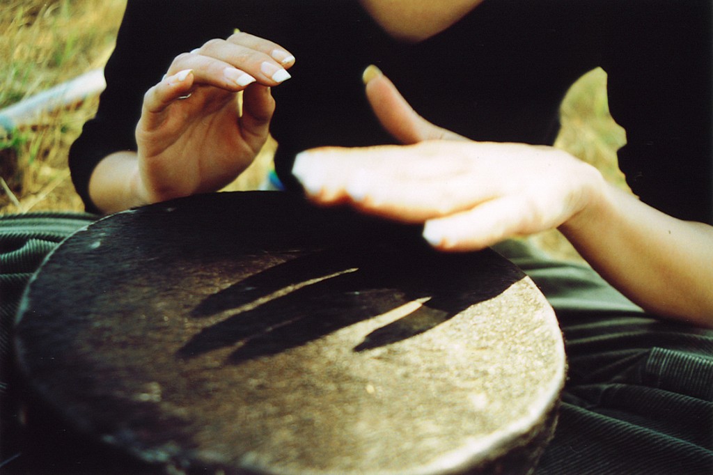 A woman plays with the variations of sound produced by her drum.